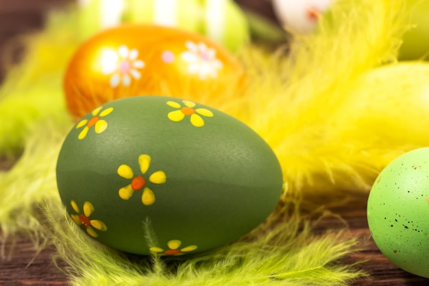 Coloridos huevos de Pascua con plumas brillantes sobre un fondo de madera oscura Primer concepto de Pascua