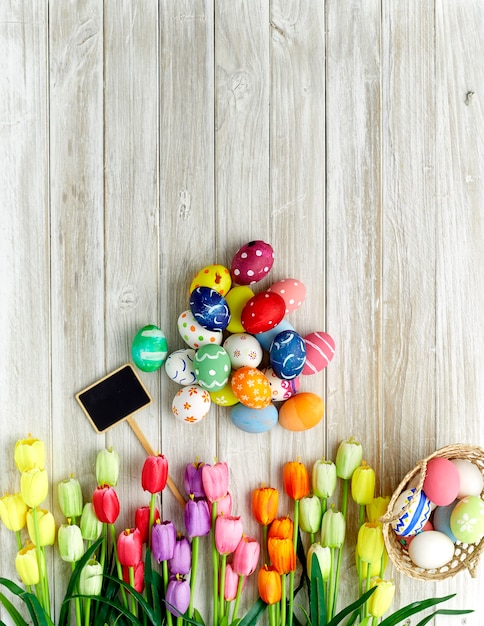 Coloridos huevos de Pascua y tulipanes en madera