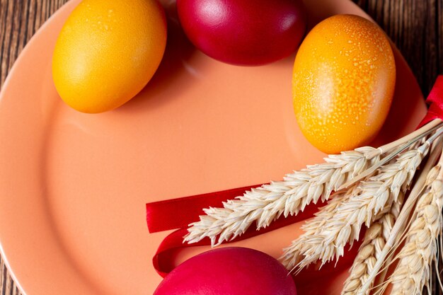 Coloridos huevos para placa de coral de Pascua con espigas de fondo de grano