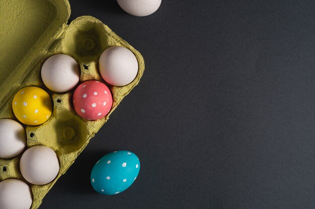 Coloridos lunares huevos de Pascua en bandeja de huevos en negro gris oscuro