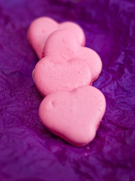 Coloridos macarons franceses con corazones sobre fondo violeta