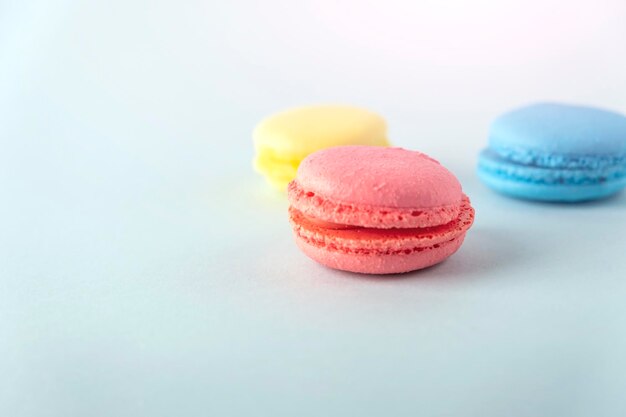 Foto coloridos macarons franceses galletas macarons sobre fondo azul postre vegetariano dulces cerrar