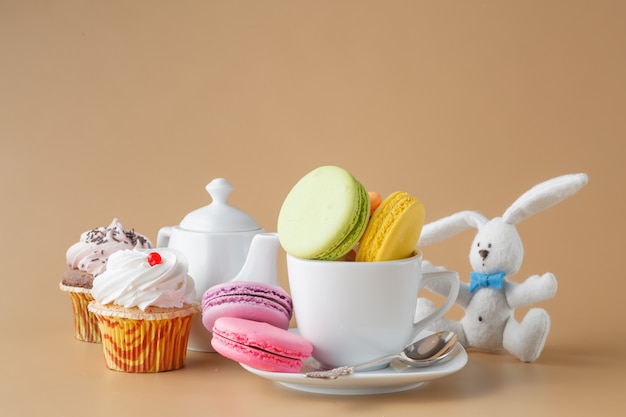 Coloridos macarons franceses y una taza de té sobre fondo beige