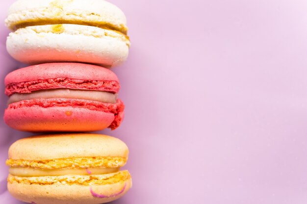 Coloridos macarons de galletas francesas en fondo rosa pastel de galletas dulces de almendra fruta sabrosa