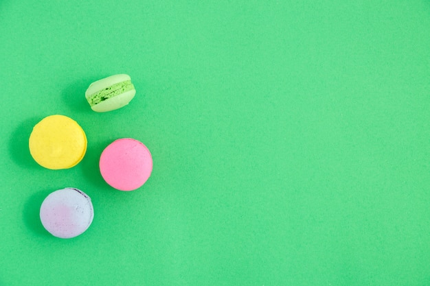 Coloridos macarons o galletas de macarrones sobre fondo verde