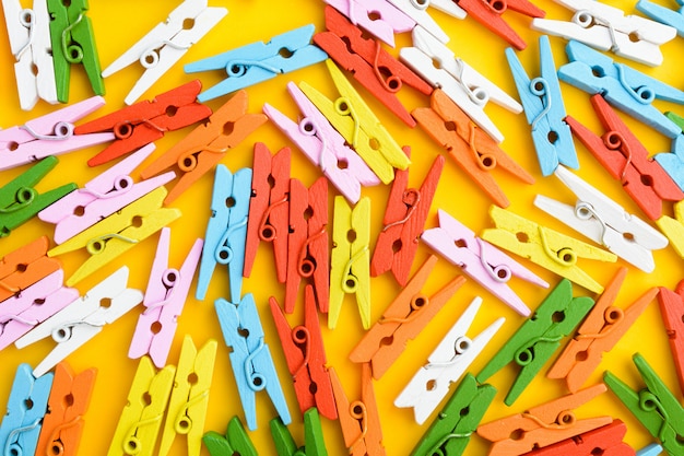 Coloridos pasadores de madera pequeños sobre papel naranja