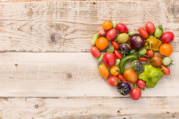 coloridos vegetales orgánicos tomates y paprika en forma de corazón sobre fondo de madera