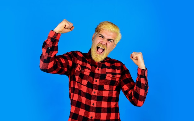 Colorir a barba é divertido. Qual estilo ter. Para uma barba cheia, cuidar da pele é fundamental. Rosto de barba por fazer de homem bonito. Camisa quadriculada de homem barbudo. Barba tingida de hipster. Cabeleireiro e barbearia.