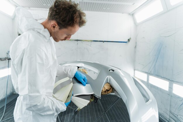 Colorista masculino selecionando a cor do pára-choque do carro com amostras de correspondência de tinta