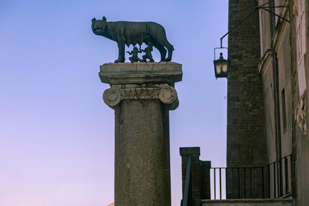 Una columna con una estatua de una loba y Rómulo y Remo