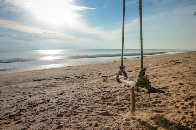 Columpio de madera colgando en la playa.