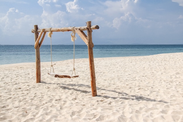 Columpio de madera en la playa de arena para el concepto de vacaciones de verano.