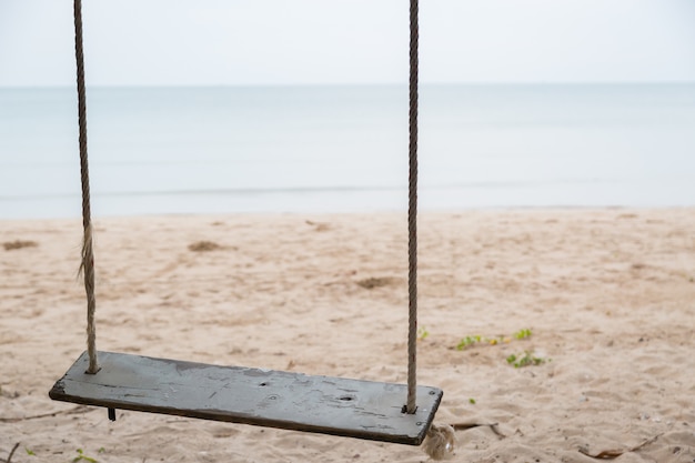 Columpio de madera en la playa y fondo de arena