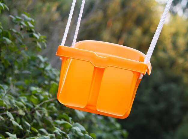 Columpio de plástico naranja en el jardín de verano