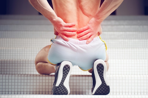 Foto coluna lesionada jovem atleta musculoso bonito com dor na coluna aptidão esportiva e conceito de cuidados de saúde