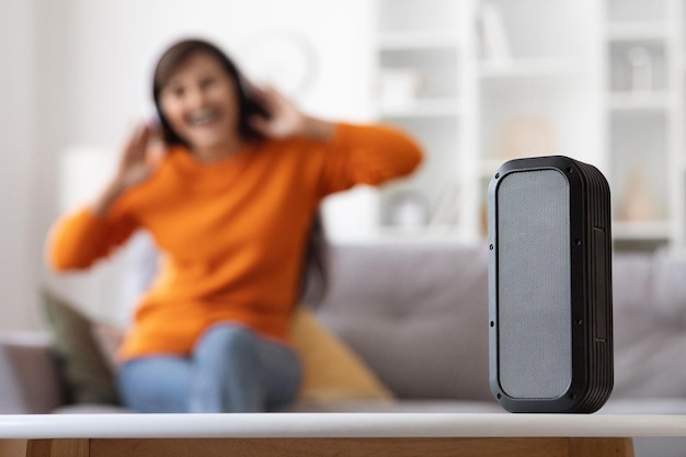 Coluna musical sem fio moderna em pé na senhora da mesa curtindo música