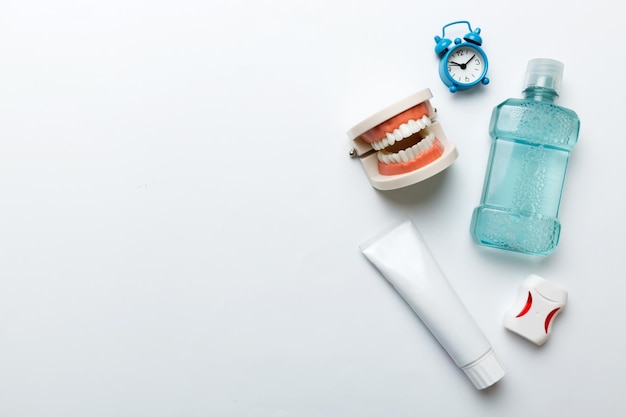 Colutório e outros produtos de higiene oral na vista de mesa colorida com espaço de cópia Postura plana Higiene dental Kit de cuidados orais Conceito de dentista