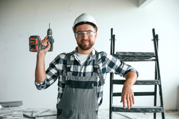 Com a broca O reparador de uniforme está no edifício inacabado