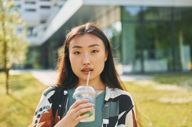 Com bebida fresca A jovem asiática está ao ar livre durante o dia
