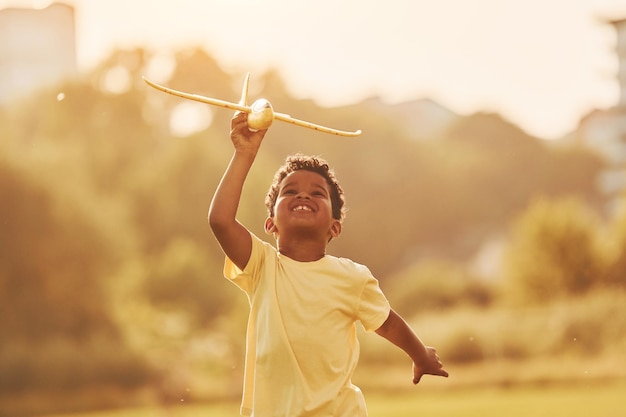 Com brinquedo nas mãos, criança afro-americana se diverte no campo no dia de verão