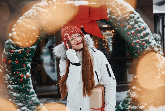 Com caixa de presente Jovem feliz em pé ao ar livre e comemorando as férias de natal