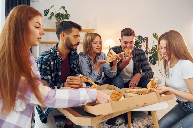 Com deliciosa pizza Grupo de amigos fazem festa dentro de casa juntos