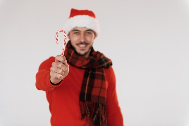 Com doces Jovem bonito em roupas de ano novo em pé dentro de casa contra fundo branco