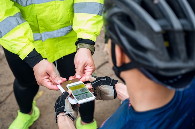 Com foco seletivo, atleta de mountain bike apresentar passaporte de saúde do certificado de vacinação em telefone na pista de corrida de bicicleta, para certificar que foi vacinado contra coronavírus. esporte durante a pandemia de covid-19.