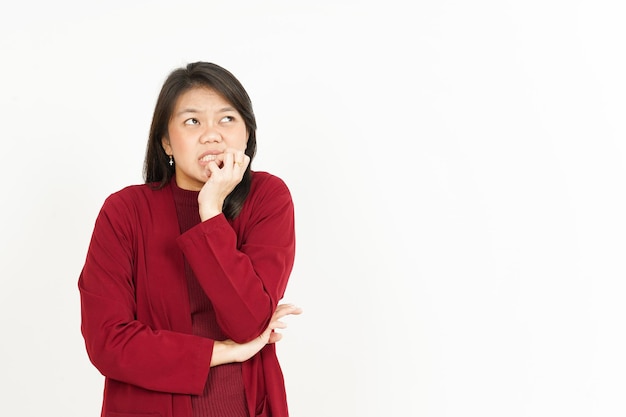 Com medo, nervoso e mordendo as unhas da bela mulher asiática vestindo camisa vermelha isolada no fundo branco