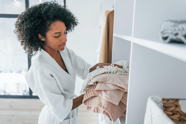 Com roupas diferentes Jovem afro-americana com cabelos cacheados dentro de casa em casa