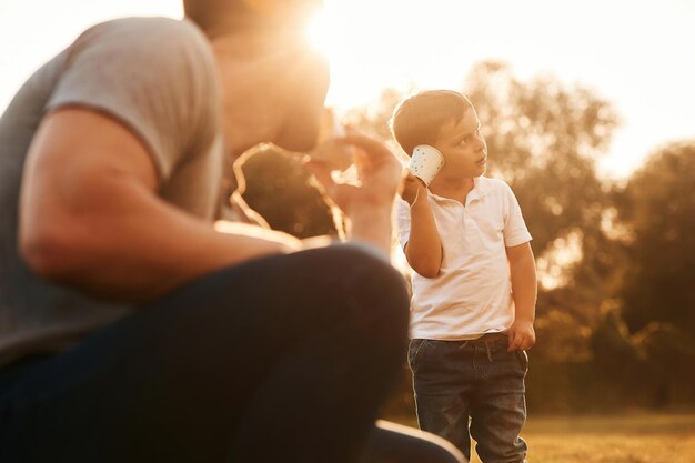 Foto com um telefone de corda, o pai e o filho estão a brincar e a divertir-se ao ar livre.