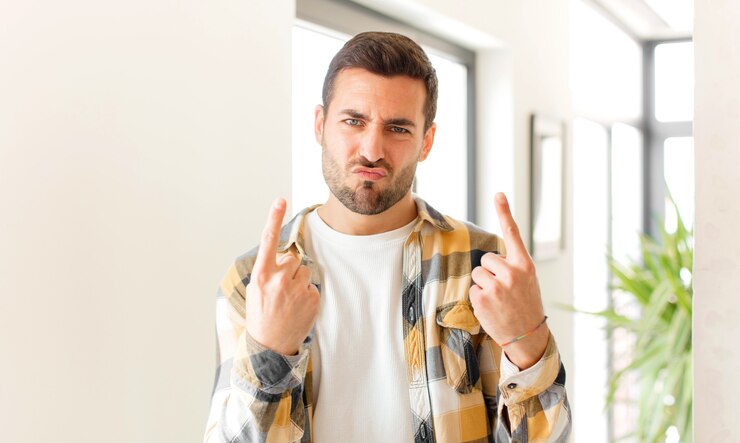 Foto com uma atitude ruim, parecendo orgulhoso e agressivo, apontando para cima ou fazendo sinal divertido com as mãos