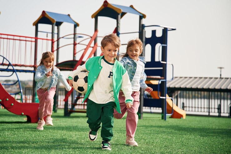 Foto com uma bola de futebol na mão, os miúdos estão a divertir-se no parque.