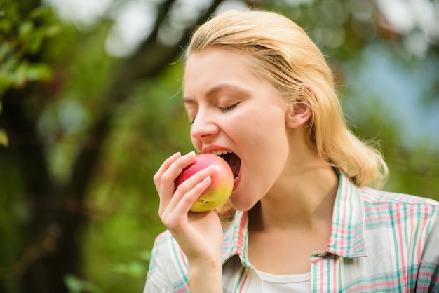 Coma frutas todos los días Mujer sostenga manzana fondo verde del jardín Producto natural orgánico Niña recolecte cosecha de manzanas en su propio jardín Estilo de vida saludable Niña agricultora sostenga manzana Concepto de cultivos locales