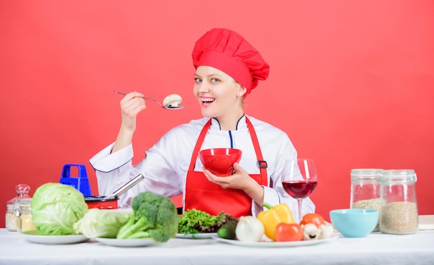 Coma saludable Ración saludable Mujer chef profesional sostenga una cuchara con champiñones crudos Concepto de dieta Chica use sombrero y delantal pruebe el sabor de los hongos Recetas vegetarianas y veganas saludables Alimentos crudos saludables