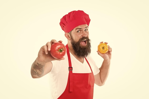 Coma tomate fresco Escolha um Conceito de culinária saudável Homem com barba em fundo branco Chef segura tomate Cozinheiro de uniforme segura legumes Receita de molho de tomate Tomate maduro para refeição deliciosa