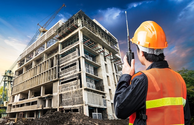 Comando do engenheiro de construção falando de um rádio portátil no canteiro de obras