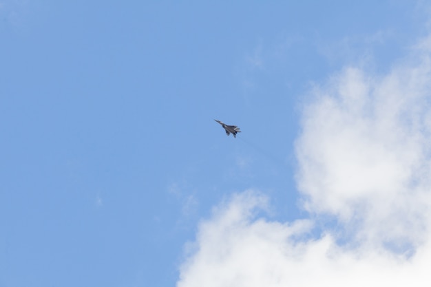 Combatiente militar en el cielo azul con nubes blancas