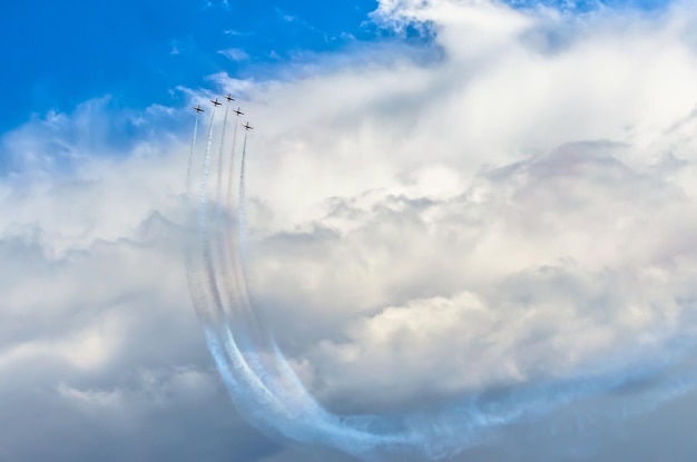 El combatiente vuela en el humo en las acrobacias aéreas del cielo azul