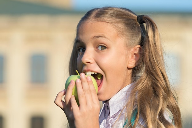 Come por salud. Niño feliz muerde la manzana al aire libre. Dieta natural. Salud dental. Higiene oral. Clínica dental. Hábitos de cuidado dental. Prevención de caries. Cuidado y salud infantil. Fruta para la salud de los dientes.