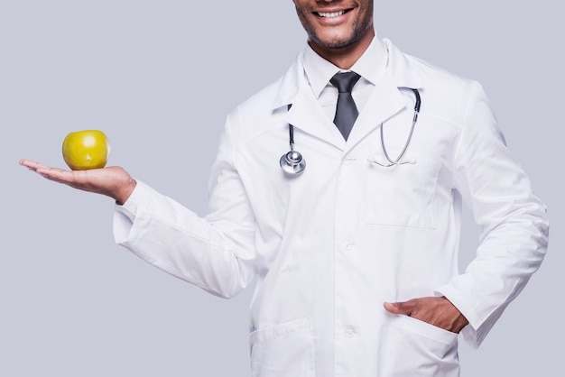 ¡Come sano! Imagen recortada del médico africano estirando manzana verde