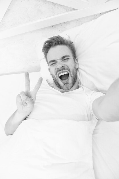 Foto começo do bom dia tempo de selfie homem feliz faz selfie no telefone bom dia homem bonito tomando selfie com celular enquanto estava deitado na cama homem tirando uma selfie na cama olá