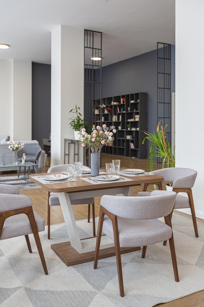 Comedor y área de cocina en un diseño interior moderno y minimalista enorme apartamento luminoso con un plan abierto en estilo escandinavo en colores azul blanco y azul oscuro con columnas en el centro