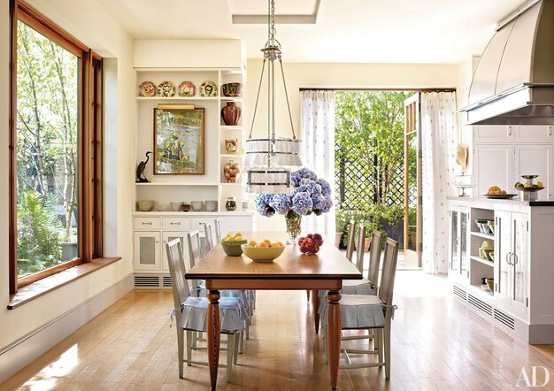 un comedor con una mesa y sillas y una mesa con un jarrón de flores en él