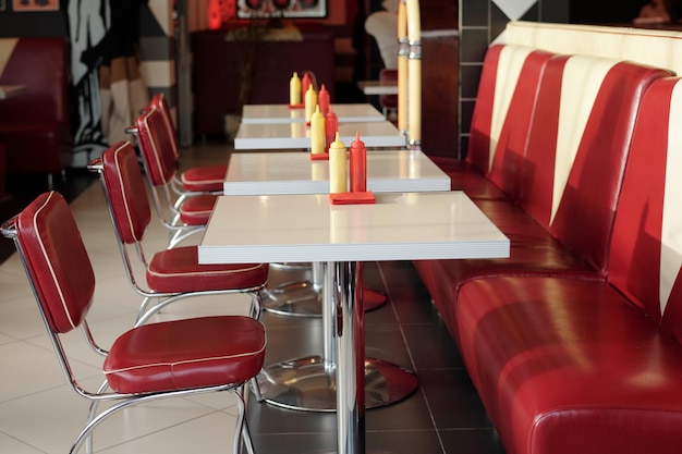 Comedor retro vacío con asientos de cuero rojo y mesas blancas