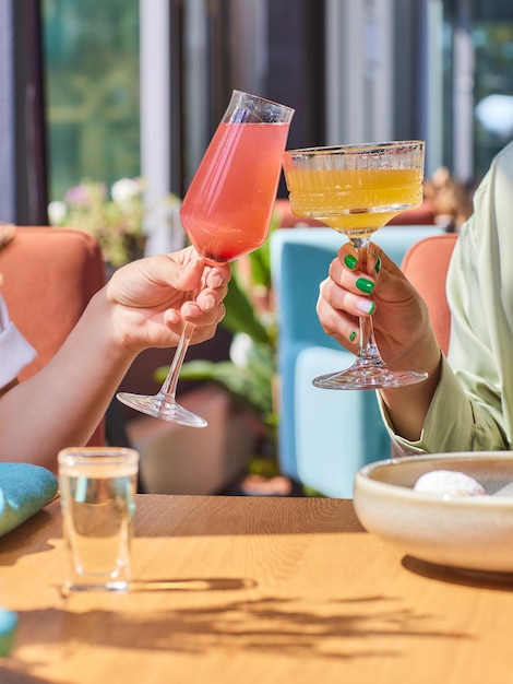 Comemorando com copos de álcool nas mãos Felizes amigas se divertindo