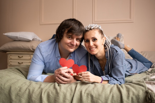 Comemorando o Dia dos Namorados. Homem e mulher em casa beijando com dia dos namorados de coração vermelho nas mãos.