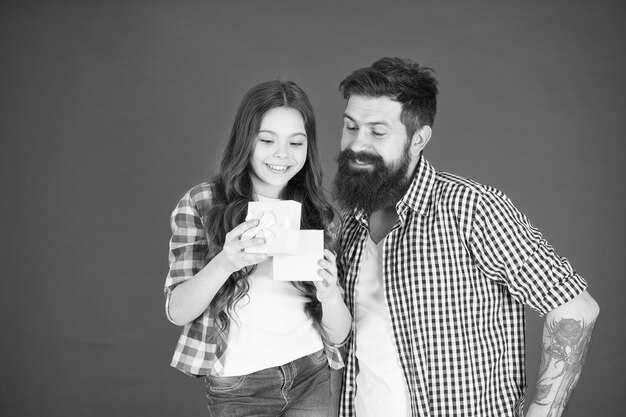 Comemore o dia dos pais Conceito de valores familiares Relações amigáveis Pai hipster e sua filha Surpresa de presente Celebração familiar Homem pai barbudo e filha menina bonitinha fundo vermelho