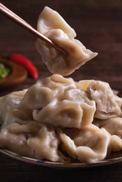 Comendo bolinhos cozidos frescos e deliciosos, jiaozi no fundo da mesa de madeira com molho de soja