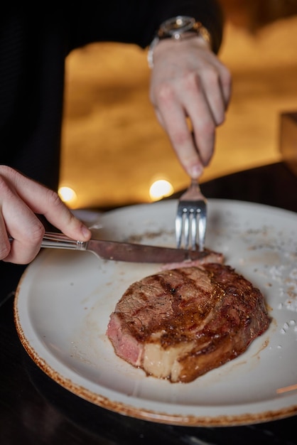 Comendo estaca de prato com garfo e faca mãos de homem